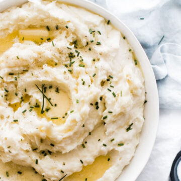 Pressure cooker mashed potatoes in a white bowl, garnished with chives.
