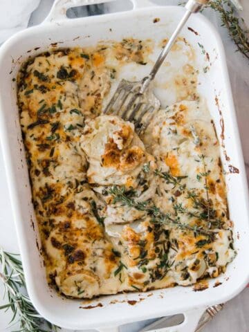Au gratin cheesy potatoes in a pan with serving fork