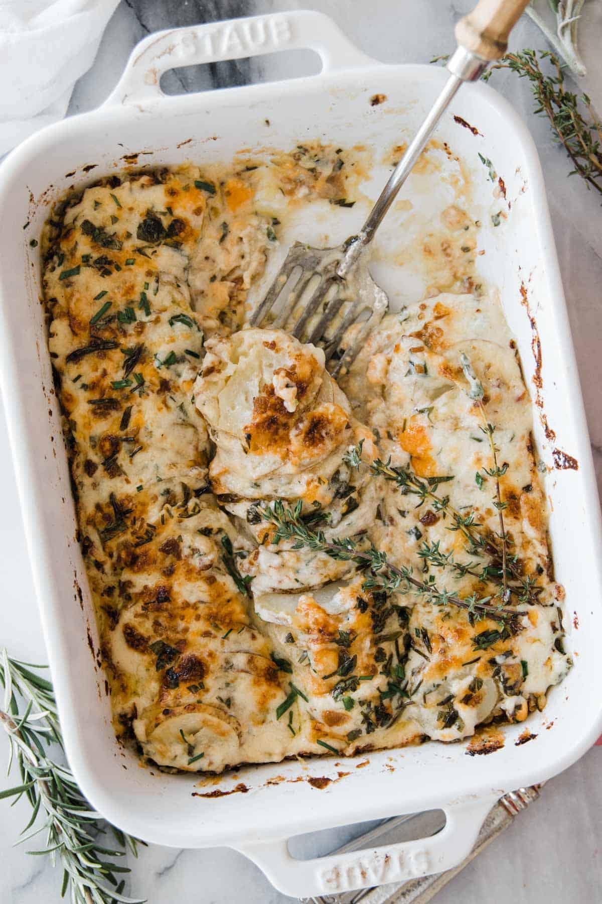 Au gratin cheesy potatoes in a pan with serving fork 