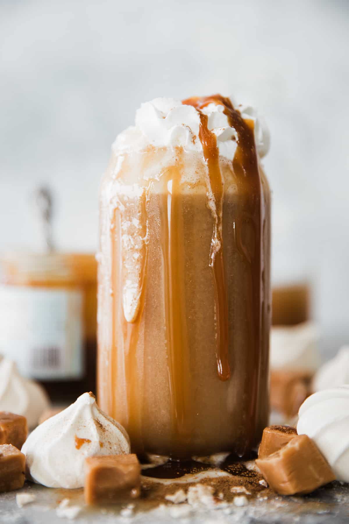 Tall glass of creamy apple juice topped with whipped cream and caramel drizzle. 