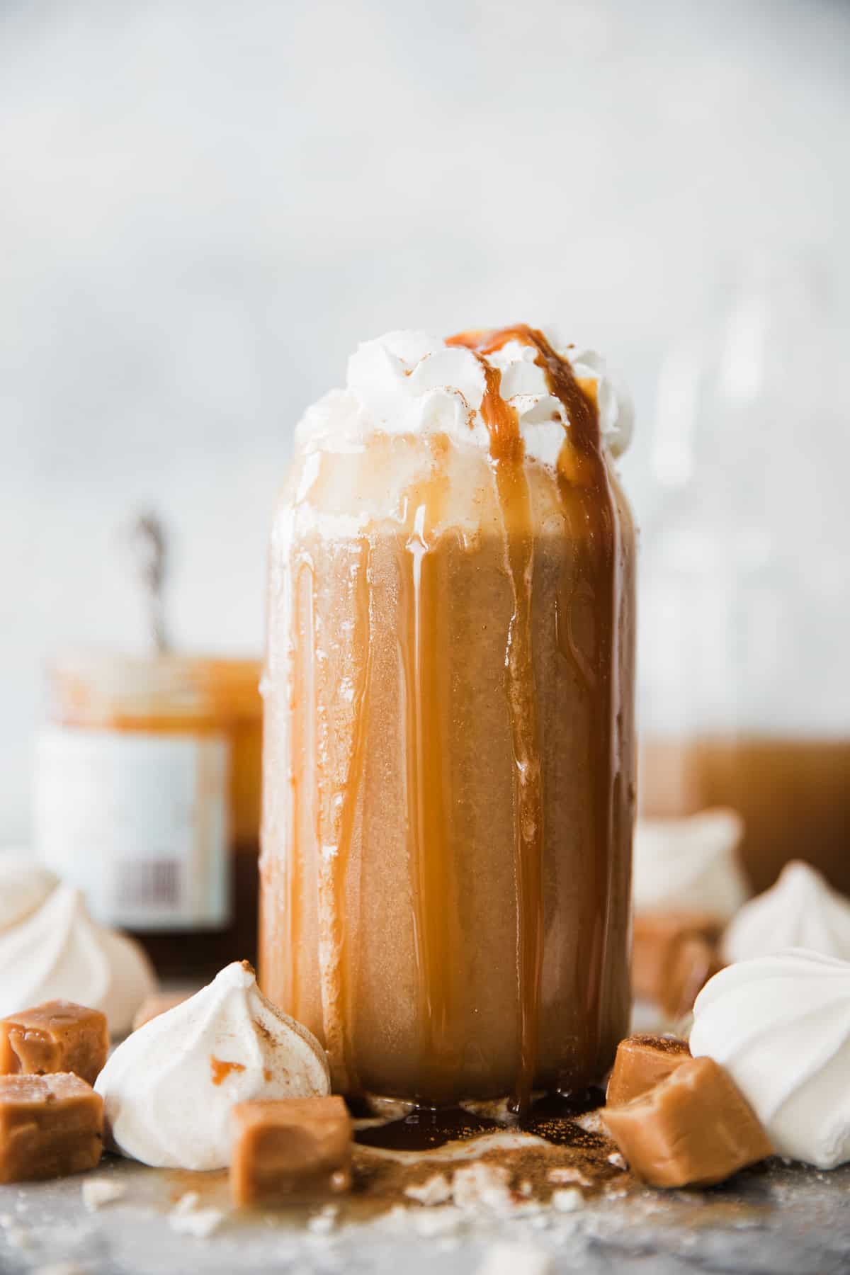 Tall glass of creamy apple juice topped with whipped cream and caramel drizzle. 