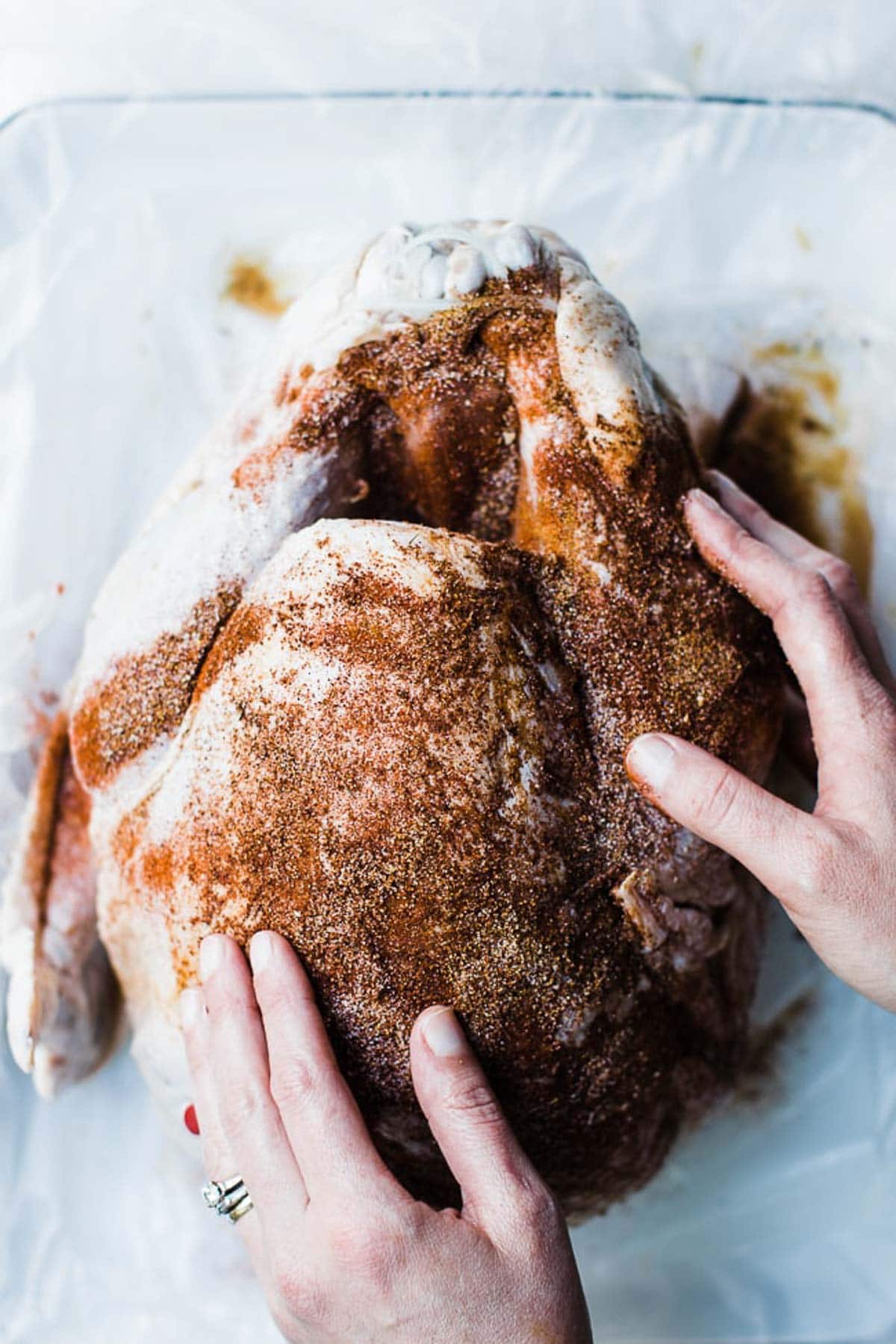 hands rubbing the spices on the outside of the turkey