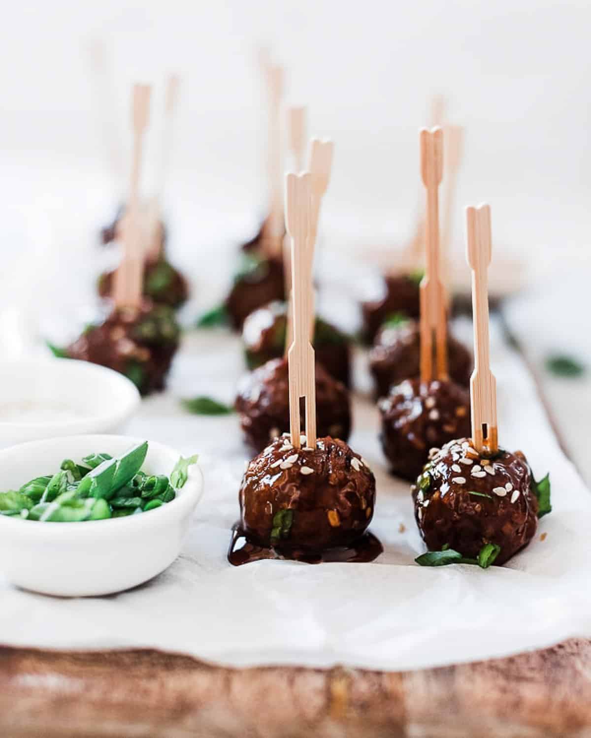 Mongolian meatballs on a wooden tray with wooden skewers inserted.