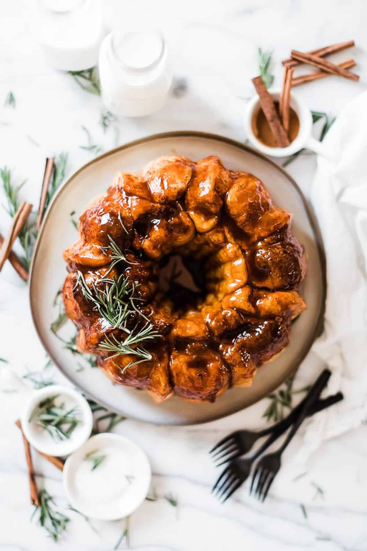 An overhead shot of easy monkey bread. There are bowls of cinnamon and rosemary to the side.