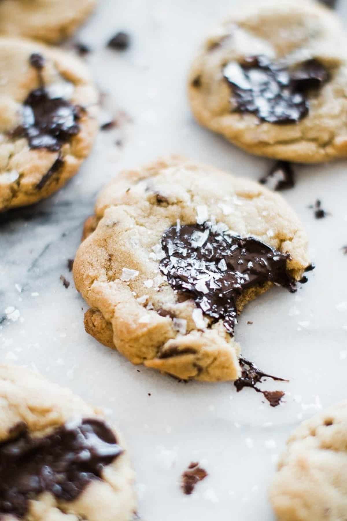 one chocolate chip cookie with salt on top and a bite taken out