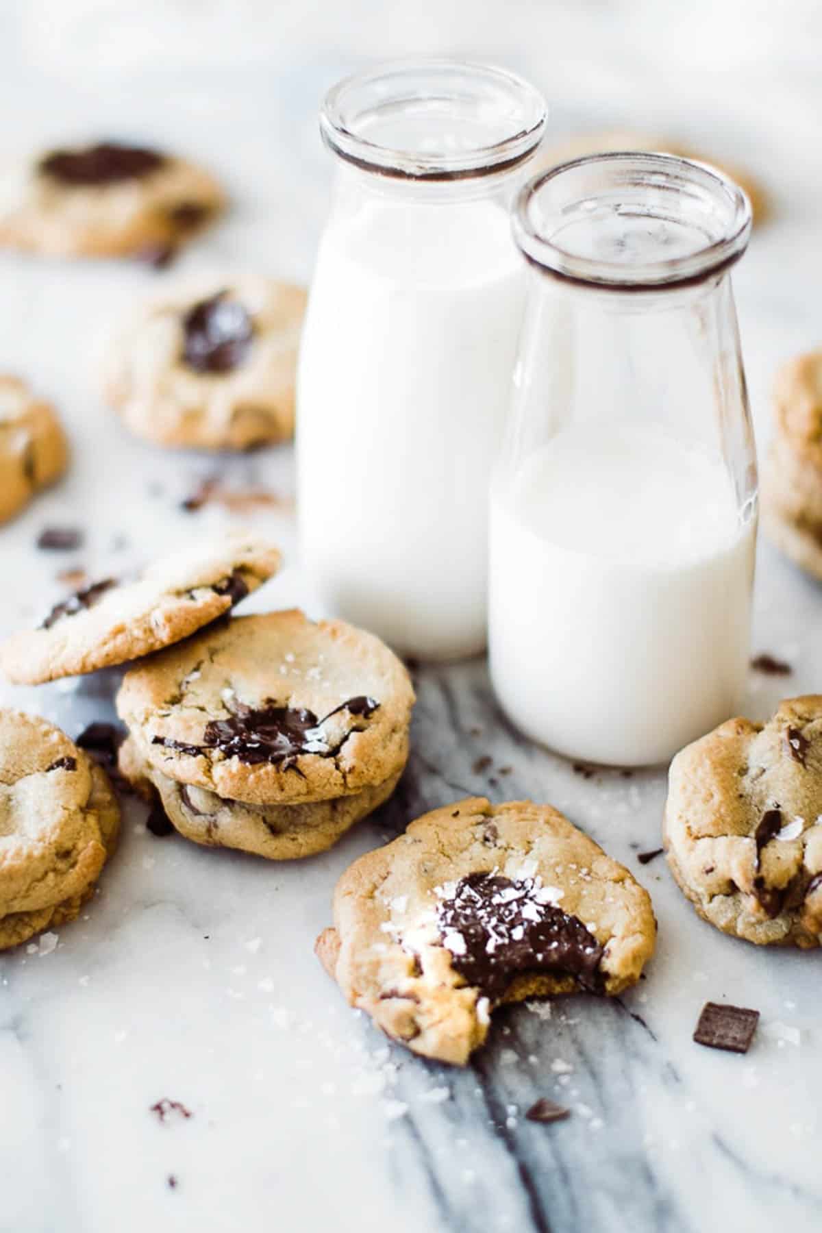 small bottles of milk with chocolate chip Cookies around them