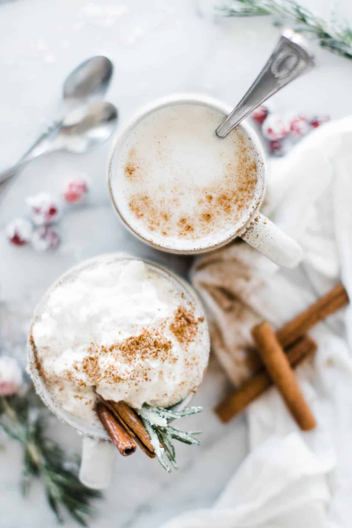 two mugs one with whip cream and another with cinnamon on top