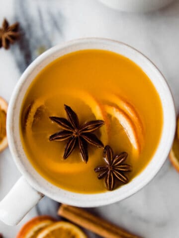 mug of orange cider recipe with oranges and star anise
