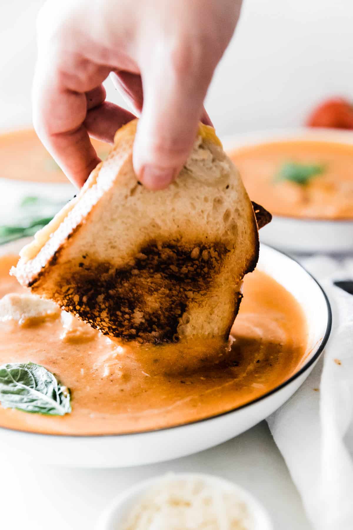 A grilled cheese sandwich being dipped into instant pot tomato soup.