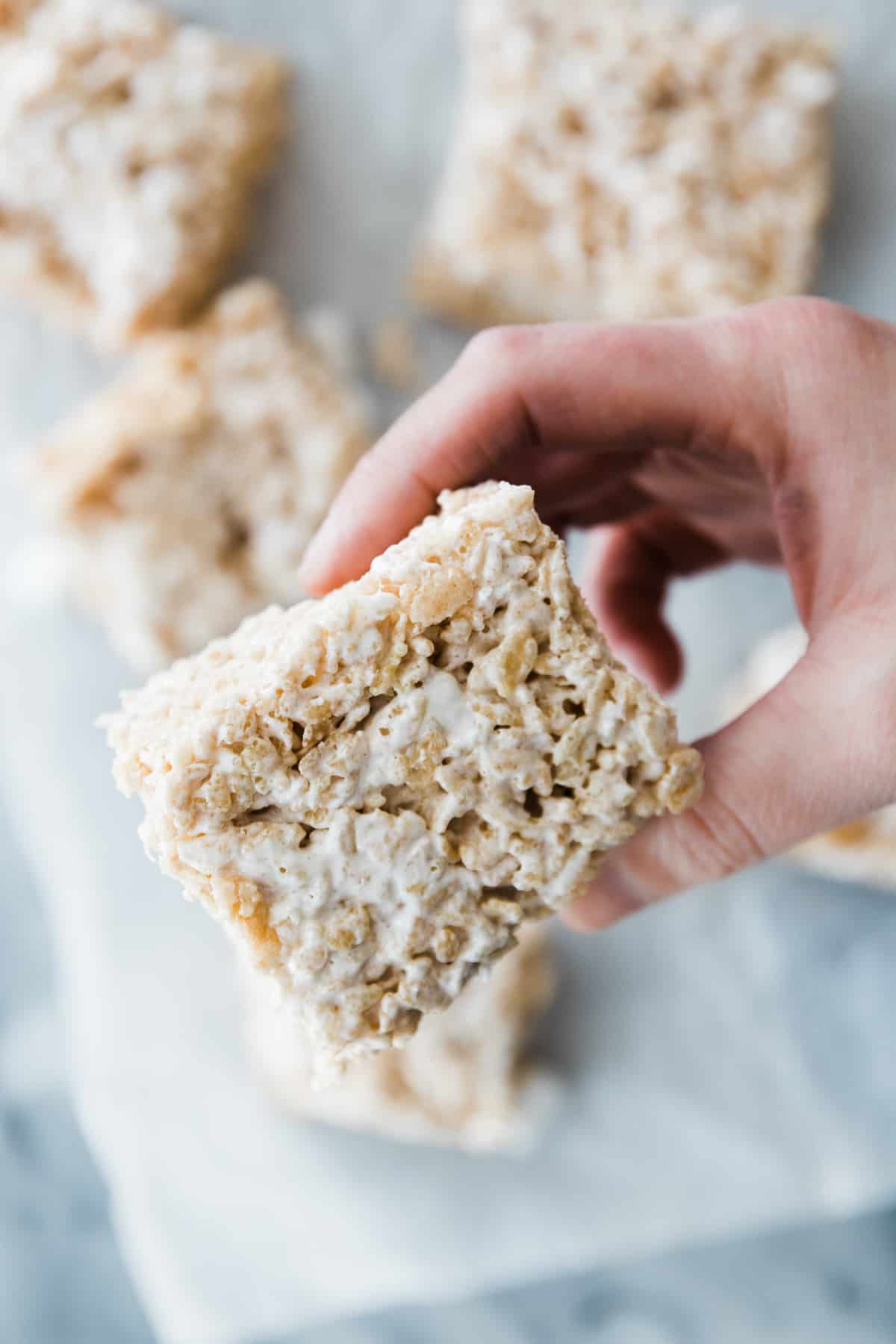 one hand holding one thick and chewy brown butter Rice Krispie treat