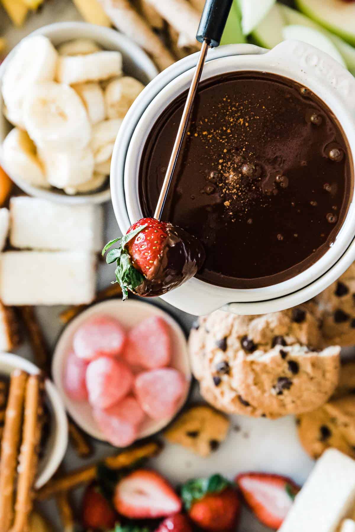 A close up of chocolate fondue with a strawberry partially dipped in chocolate set ontop.