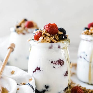Pressure cooker yogurt recipe in glass jars. They are topped with fruit and granola.