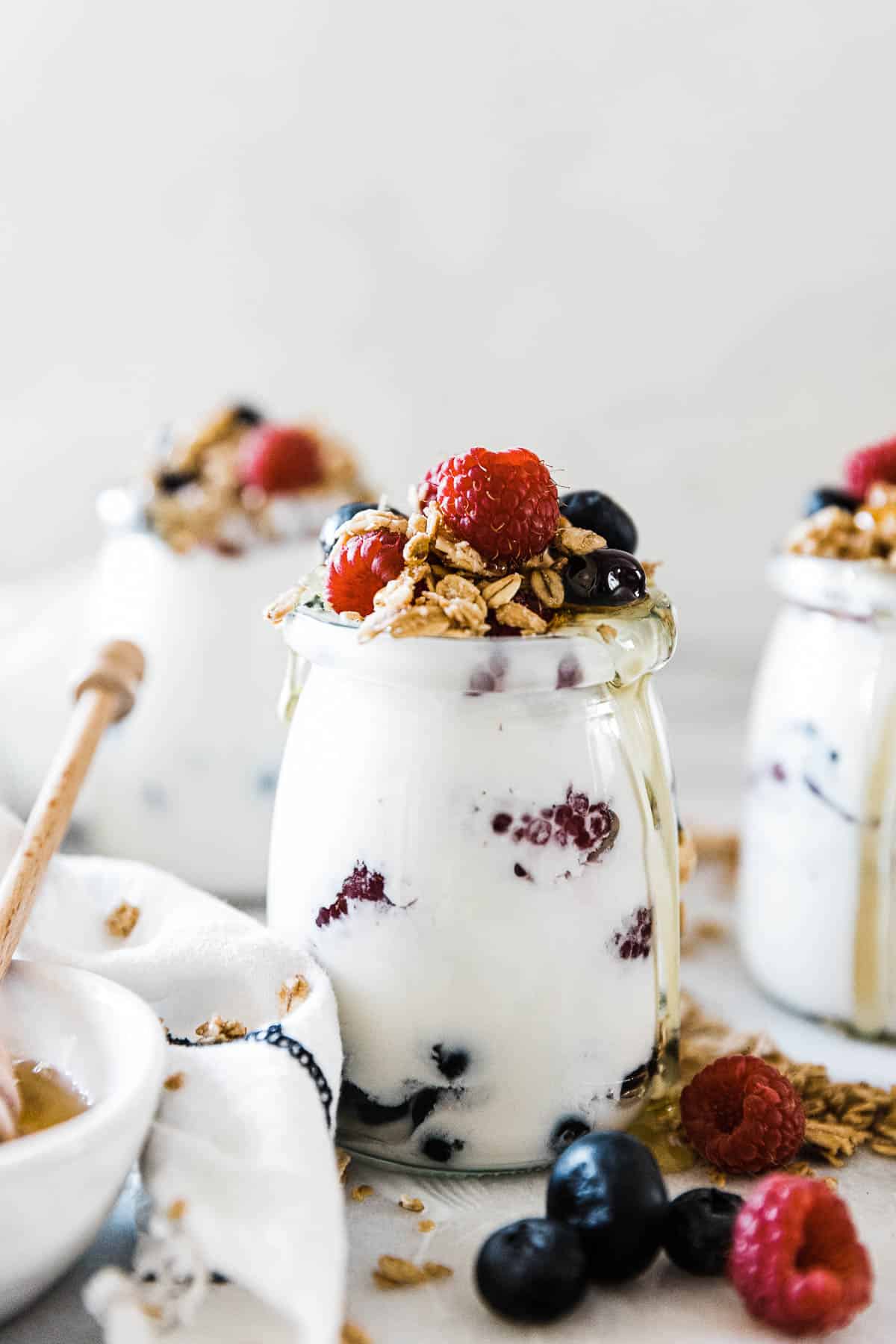 Pressure cooker yogurt recipe in glass jars. They are topped with fruit and granola.
