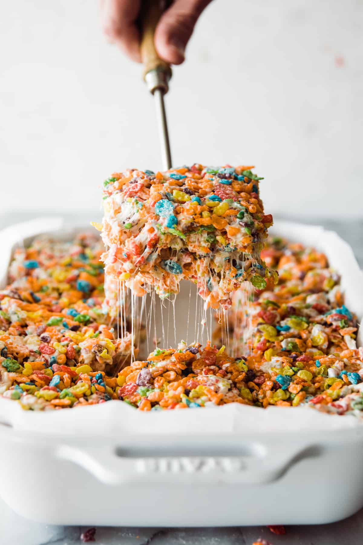 Serving spoon pulling out a brown butter fruity pebble square. 