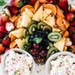 Funfetti Cake batter dip in two bowls surrounded by fruit shaped as a rainbow.