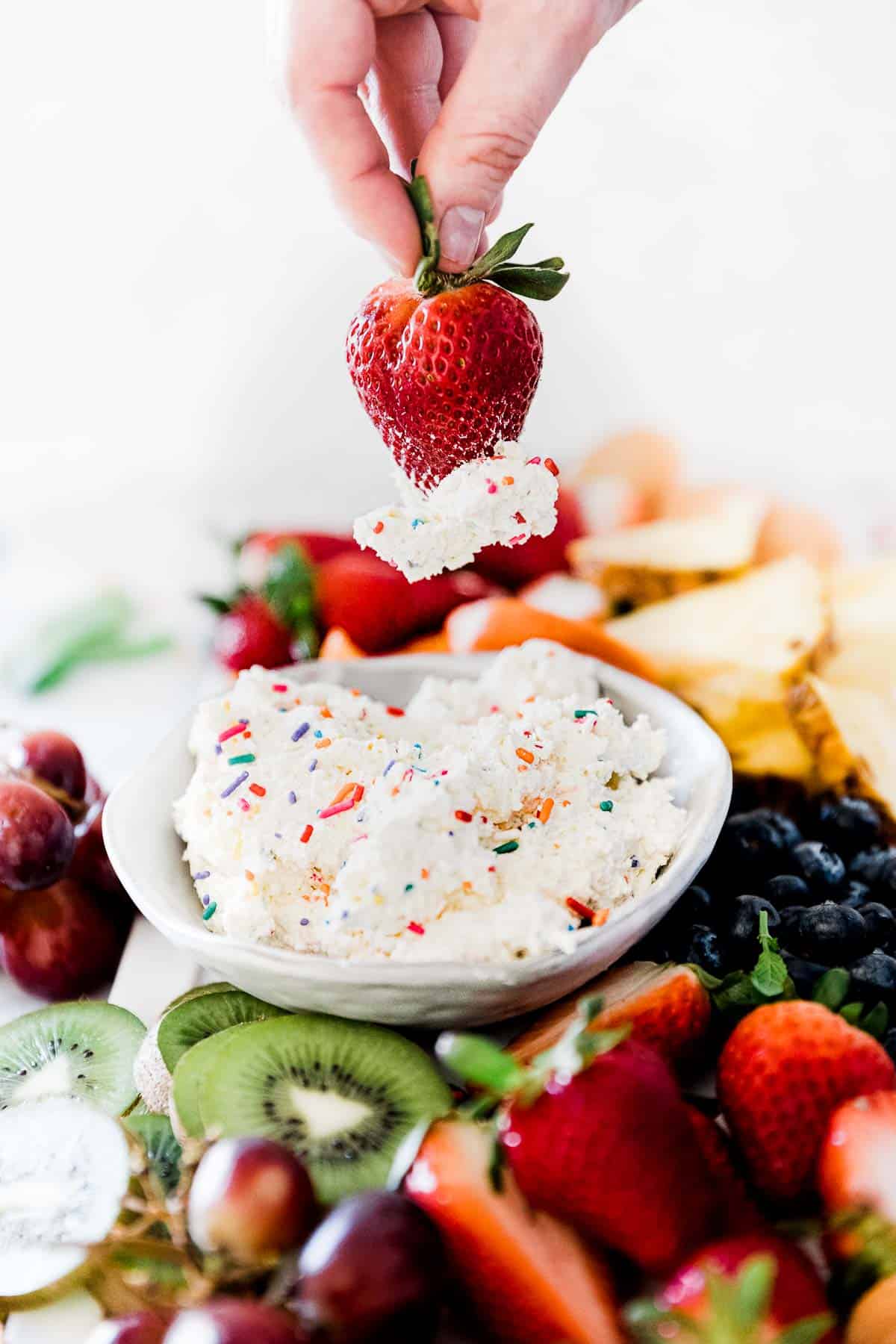 A strawberry being dipped into cake batter dip.