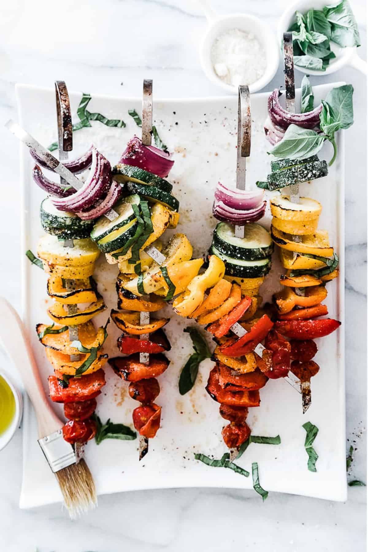rainbow vegetable skewers on a white plate and salt and pepper. 