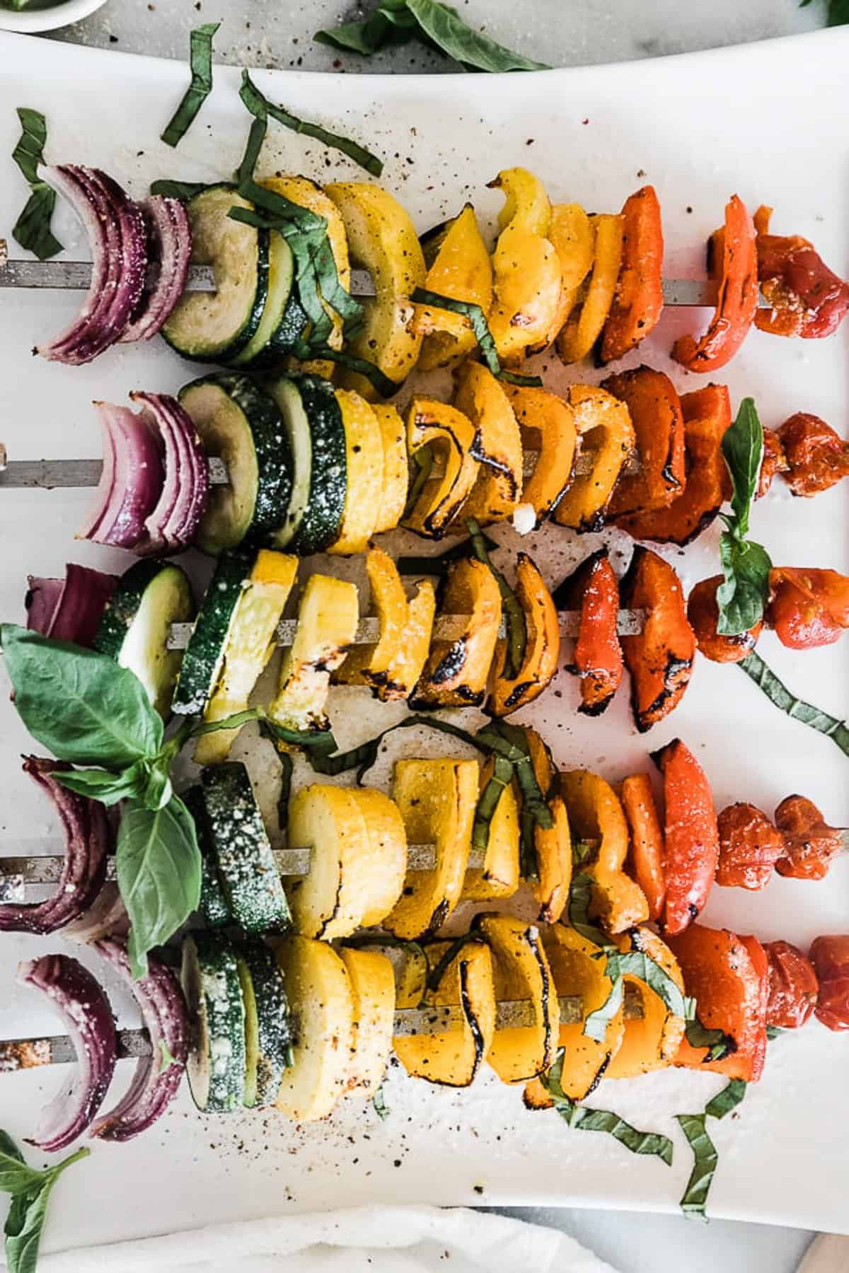 rainbow vegetable skewers on a white plate and salt and pepper. 