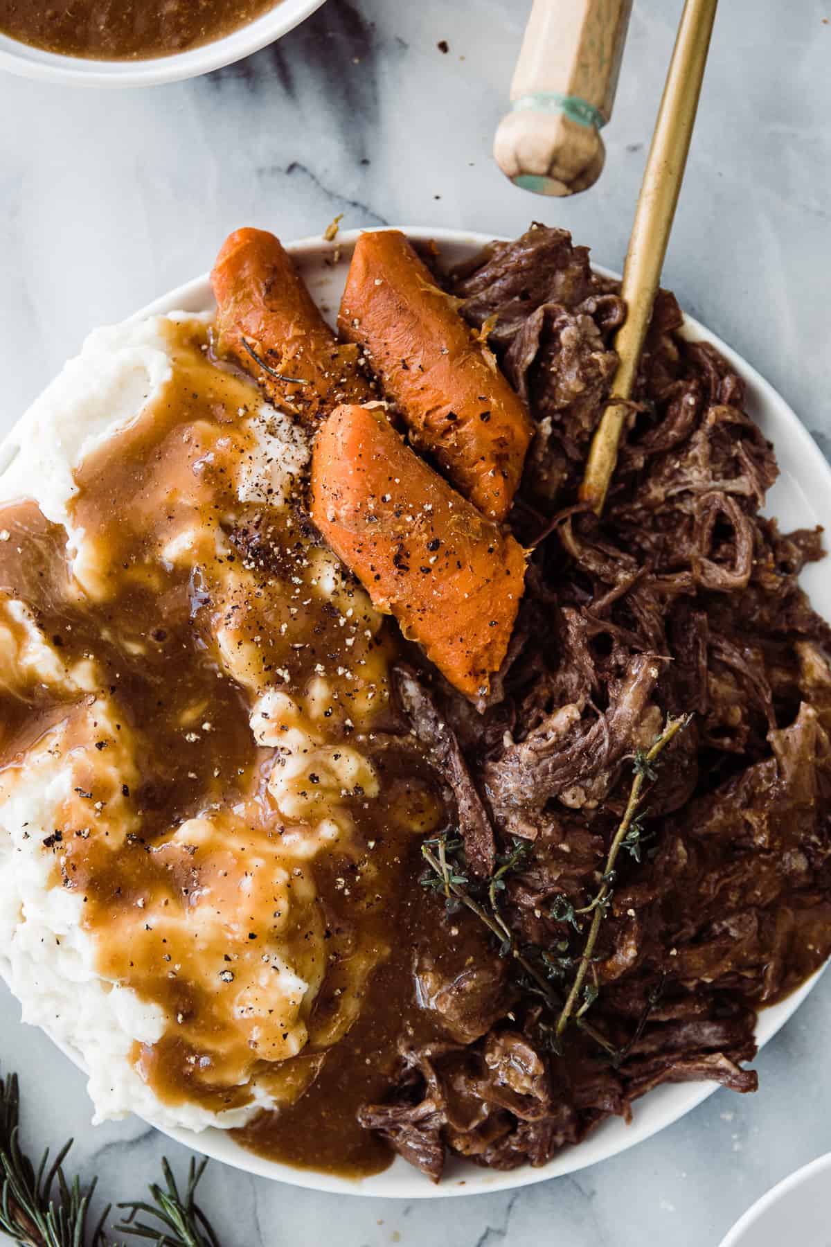 Bowl of instant pot roast beef served with mashed potatoes and carrots.