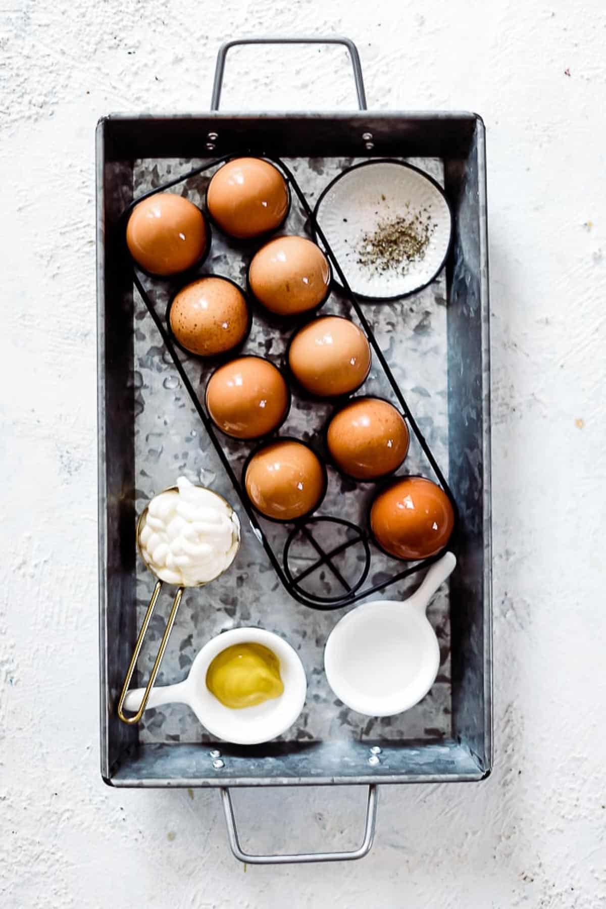 Ingredients needed to make deviled eggs in a metal tray.