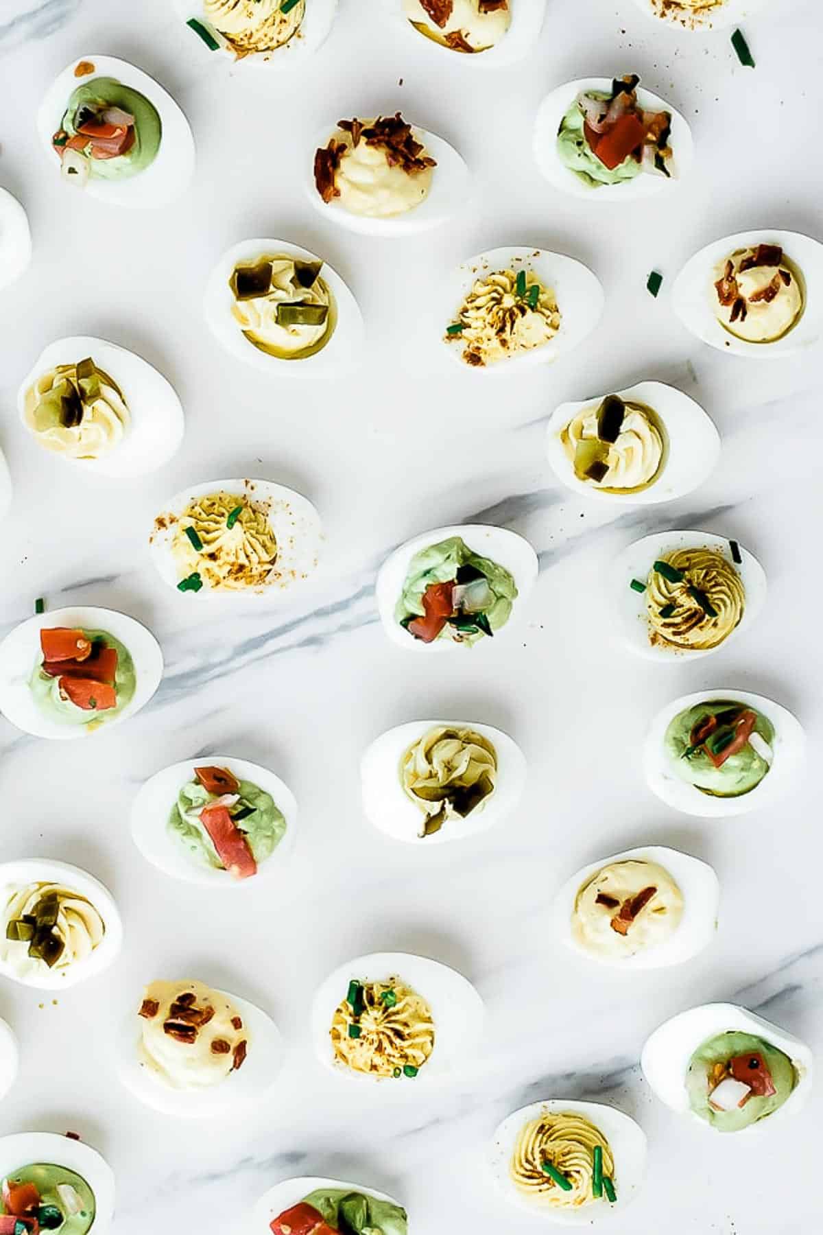 5 star deviled egg recipe on a marble counter, several scattered around and garnished in various ways.