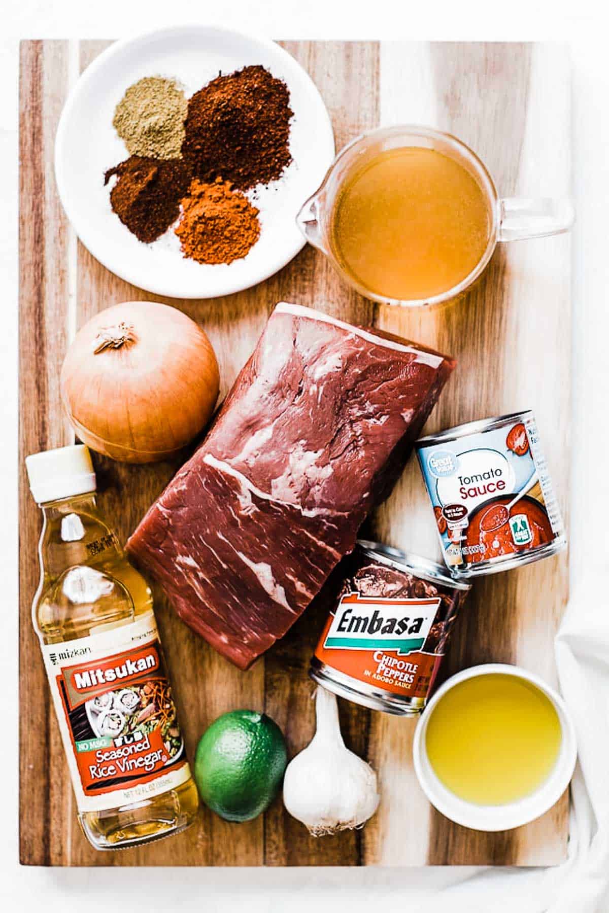 Ingredients needed for instant pot barbacoa on a wooden cutting board.