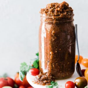 Chipotle Salsa in a mason jar surrounded by tomatoes.