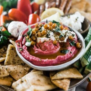Beet Hummus surrounded by pita chips and veggies.