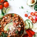 Bowl of pressure cooker pinto beans on the counter topped with avocado and cotija cheese.