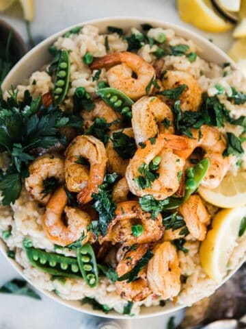 Shrimp risotto recipe in a white bowl. The dish is garnished with parsley.