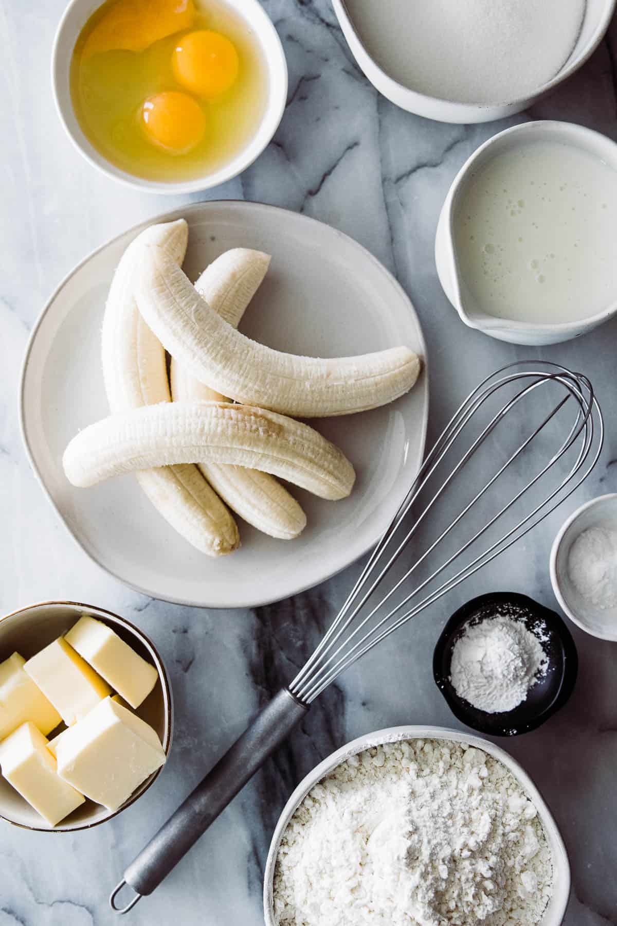 Ingredients for banana bars on a marble cutting board in bowls. 
