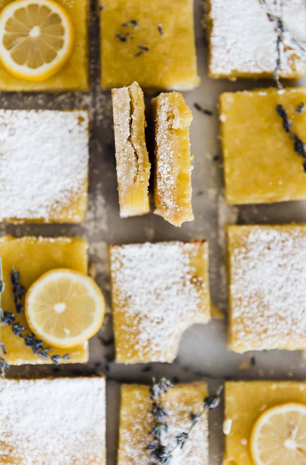 A closeup of lemon bars lined up on a marble counter.