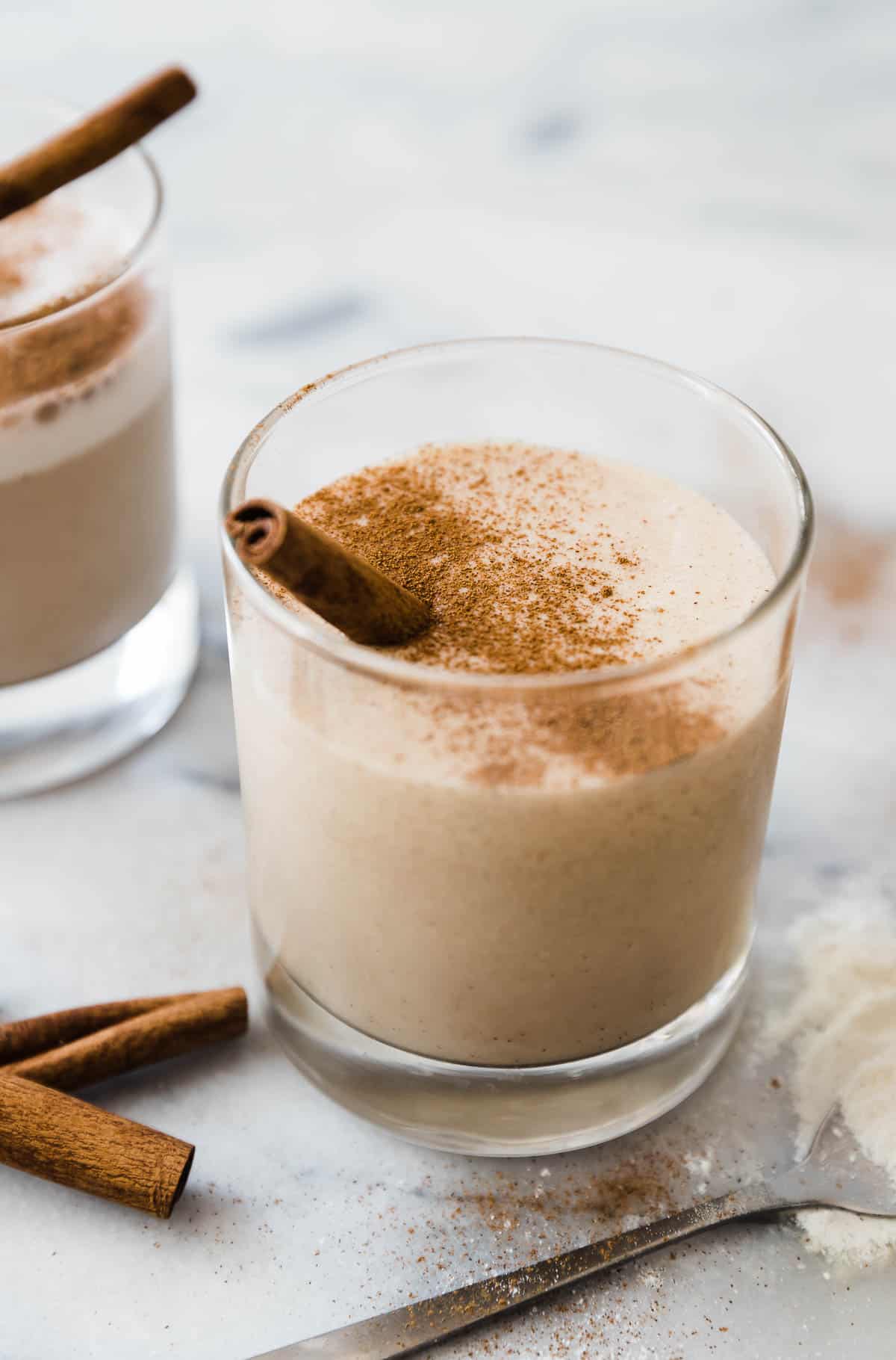 A close up of vanilla protein shake in a short glass. It is garnished with cinnamon.