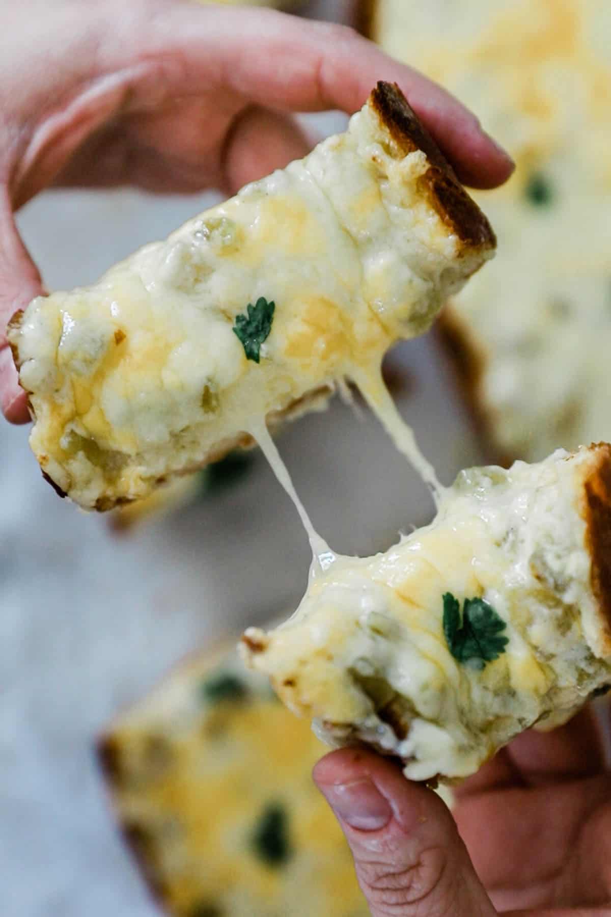 Green chilli cheese toast being pulled apart with cheese strings between slices.