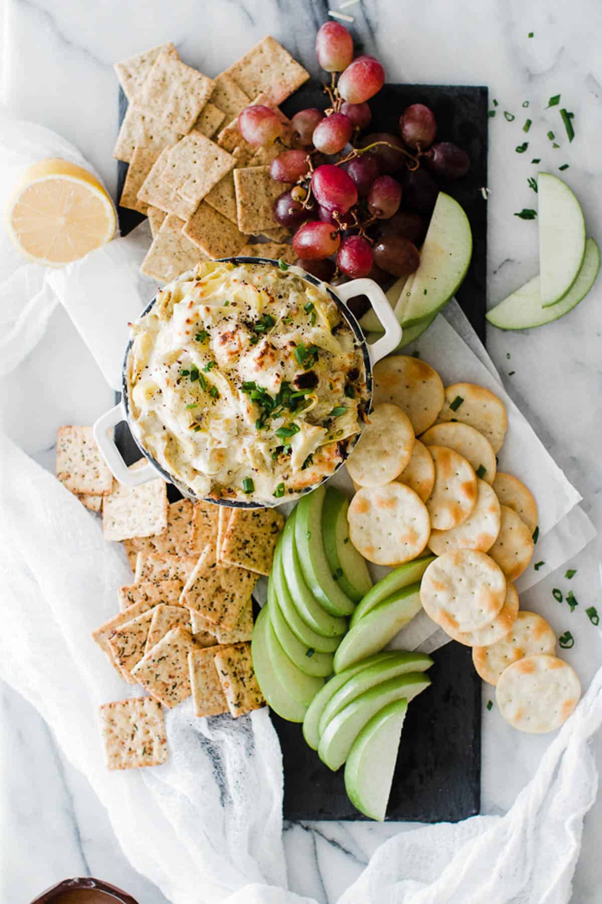 Platter with sliced apples and crackers served with hot artichoke dip.