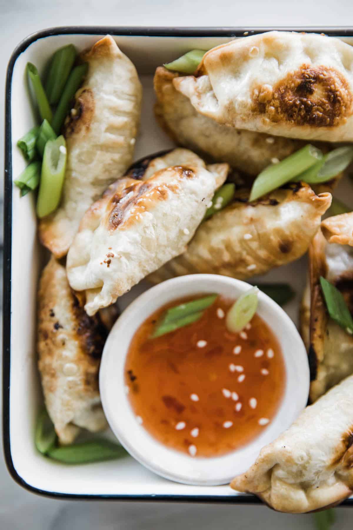 Crispy air fryer potstickers on a tray with two dipping sauces. 