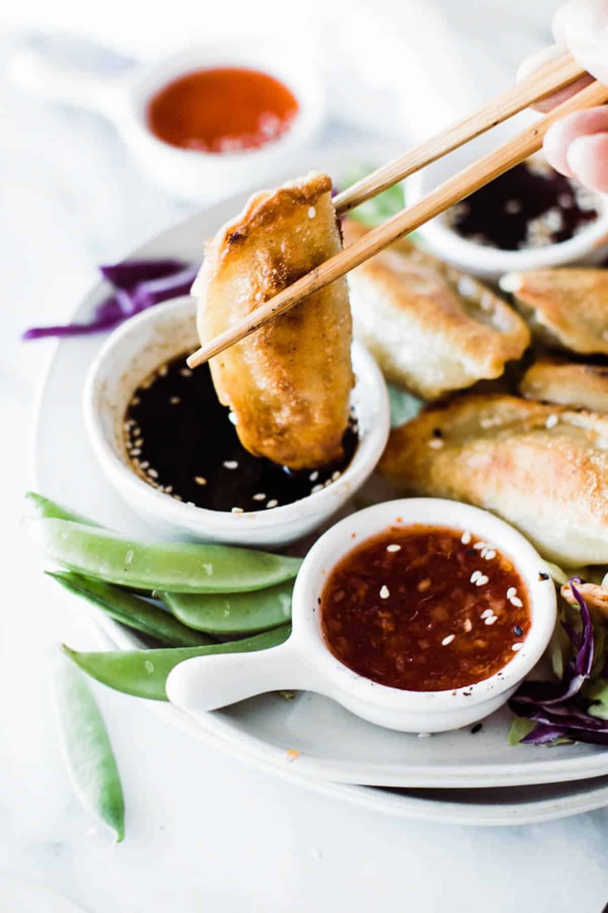 Dipping potstickers into soy sauce with sesame seed. 