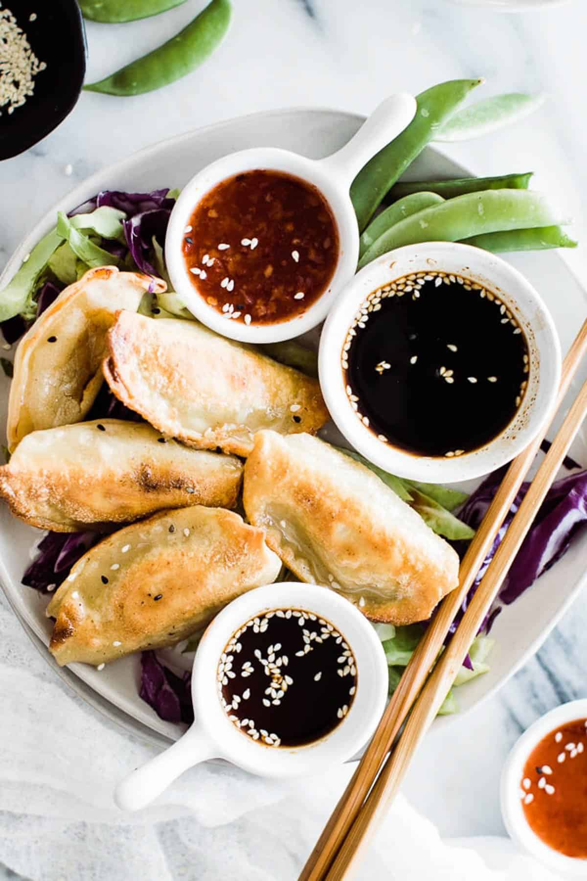 Crispy potstickers with dipping sauces and chopsticks. 