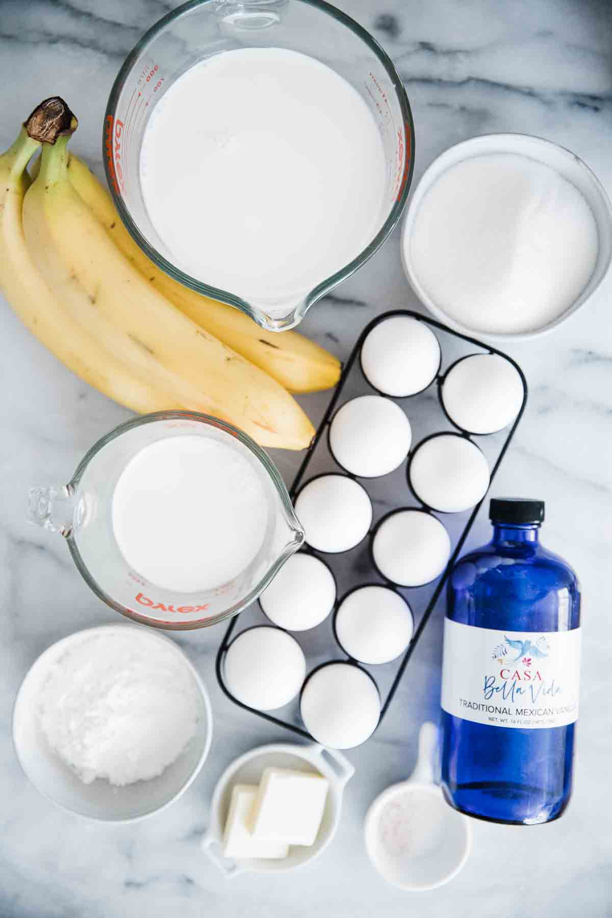 Bananas, eggs, cream, vanilla, butter, and cornstarch on a marble counter.