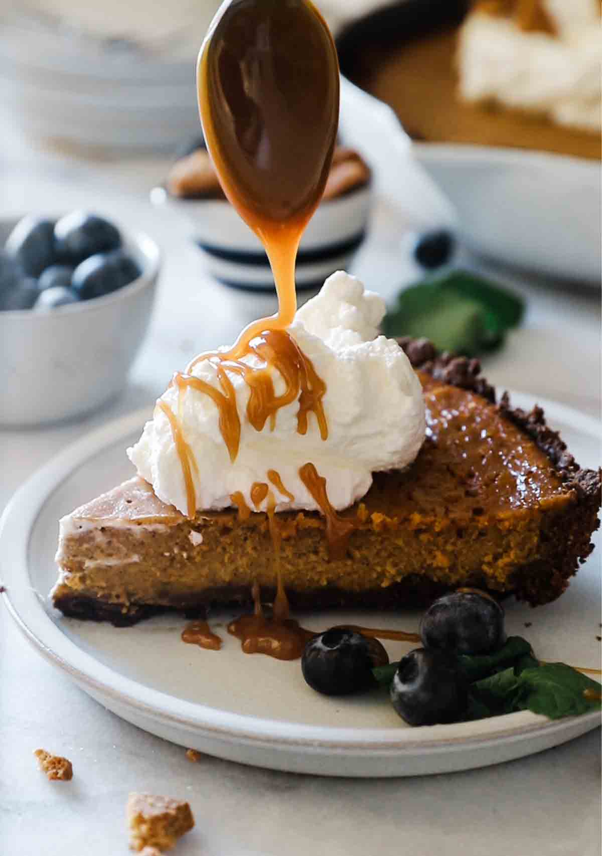 A slice of easy pumpkin pie being drizzled with salted caramel sauce.