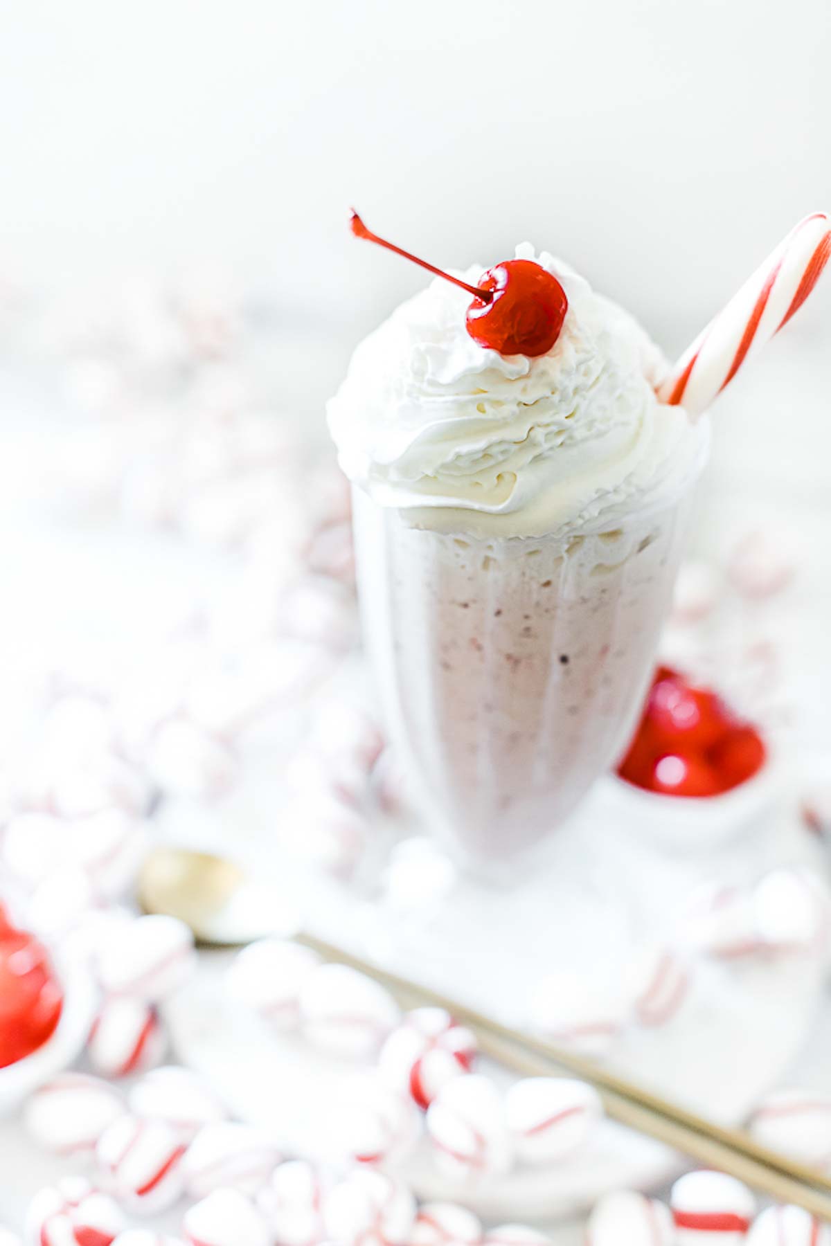 A single sundae glass filled with peppermint shake, whipped cream, and a cherry.