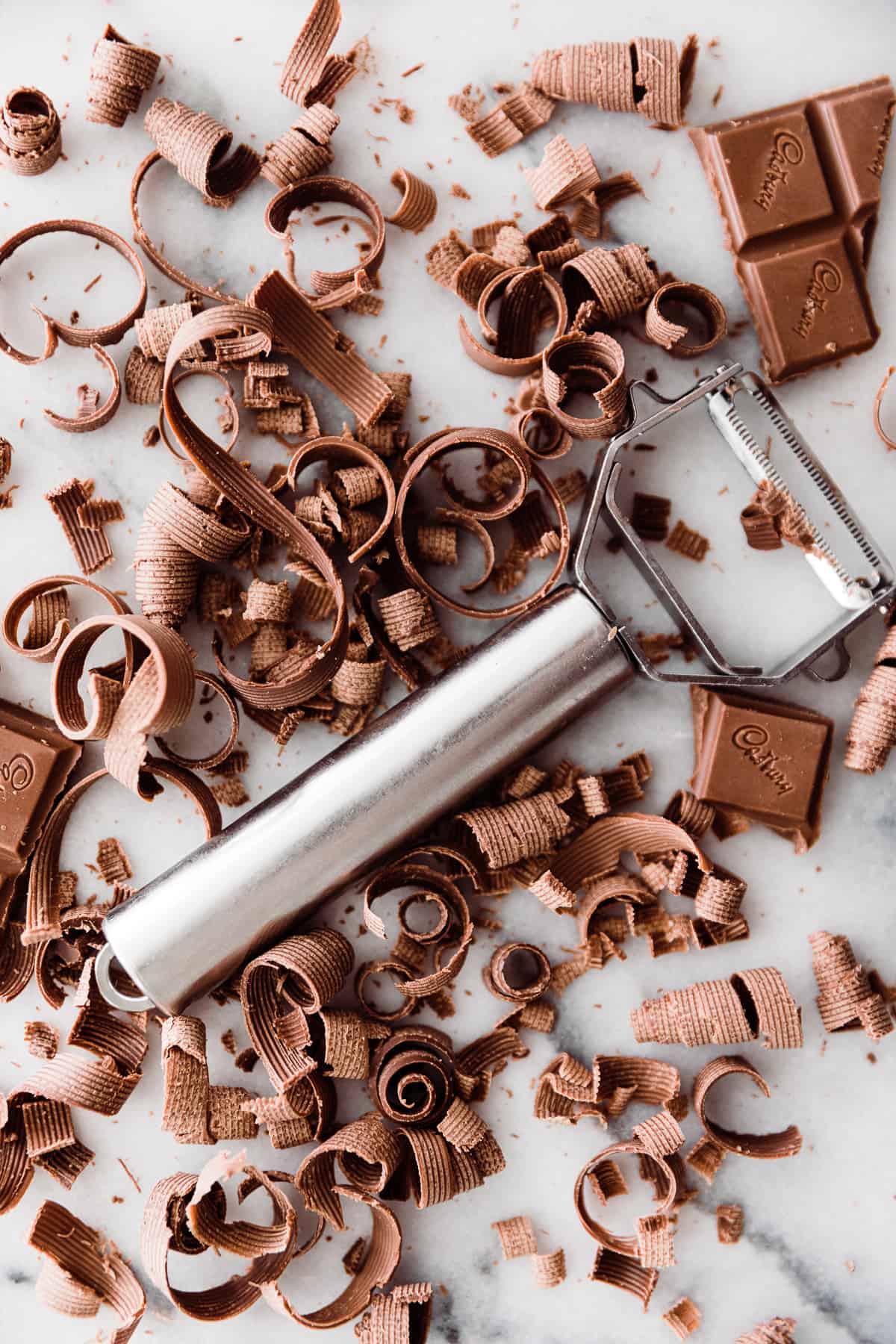 Vegetable peeler in the middle of a bunch of chocolate curls or ribbons. 