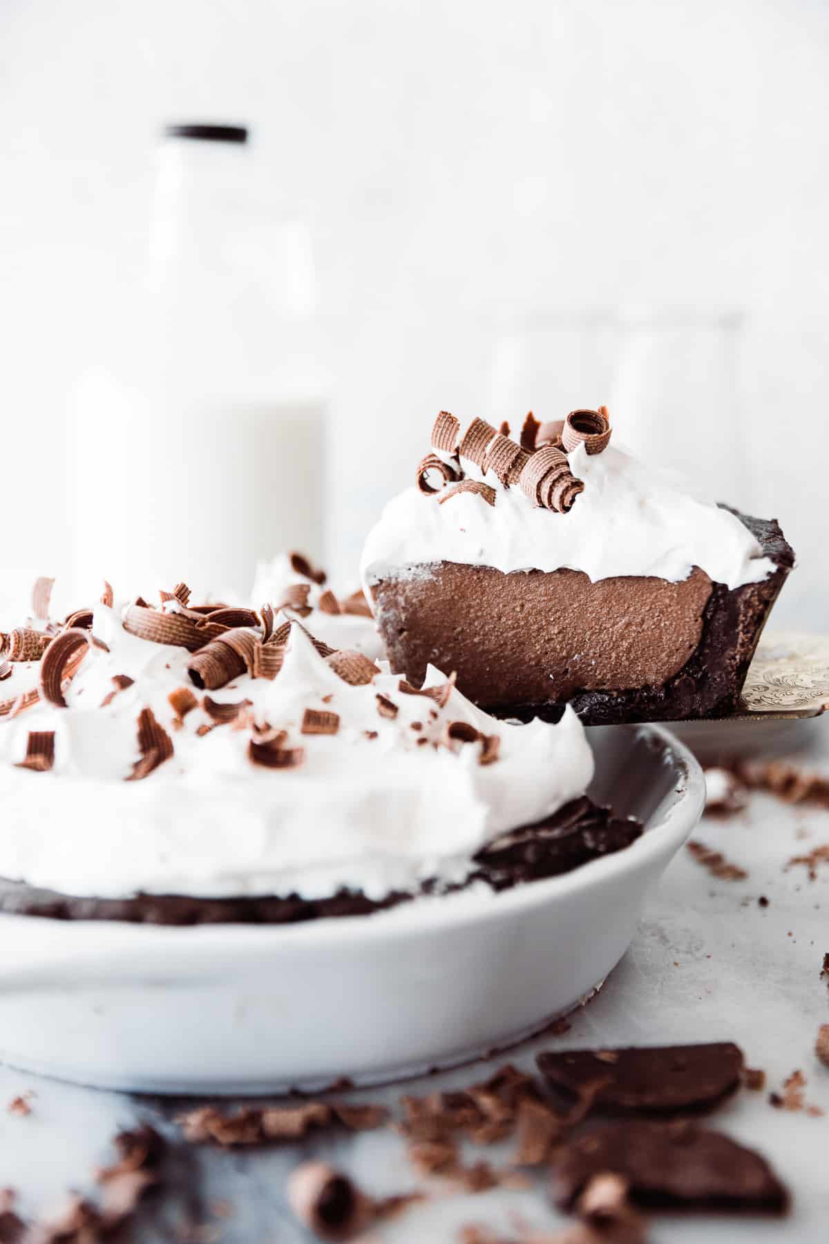 One slice of chocolate cream pie with a mint cookie pie crust being lifted out of the pie pan. 