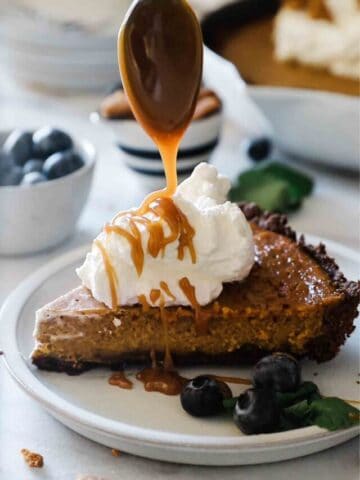 A slice of easy pumpkin pie being drizzled with salted caramel sauce.