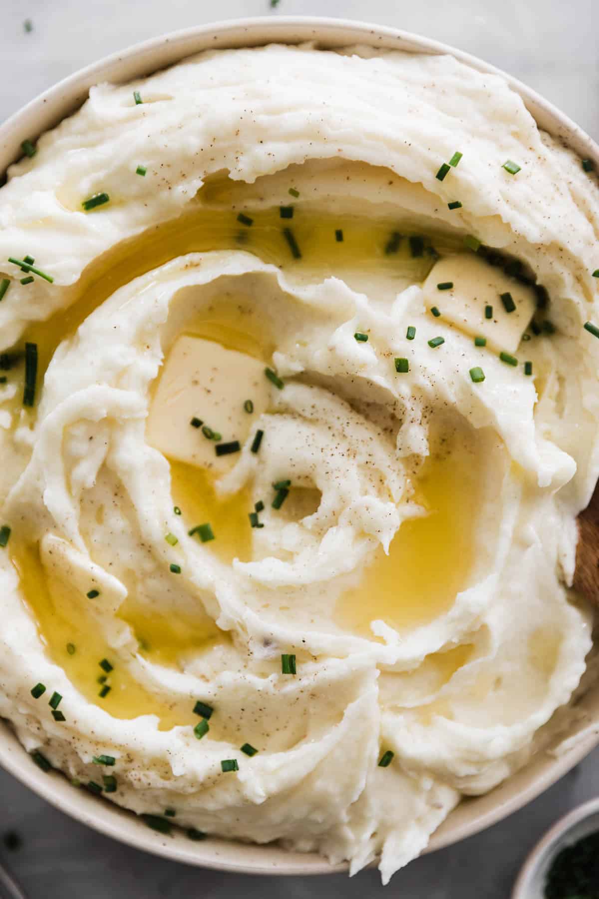 Instant pot mashed potatoes in a white bowl topped with chives.