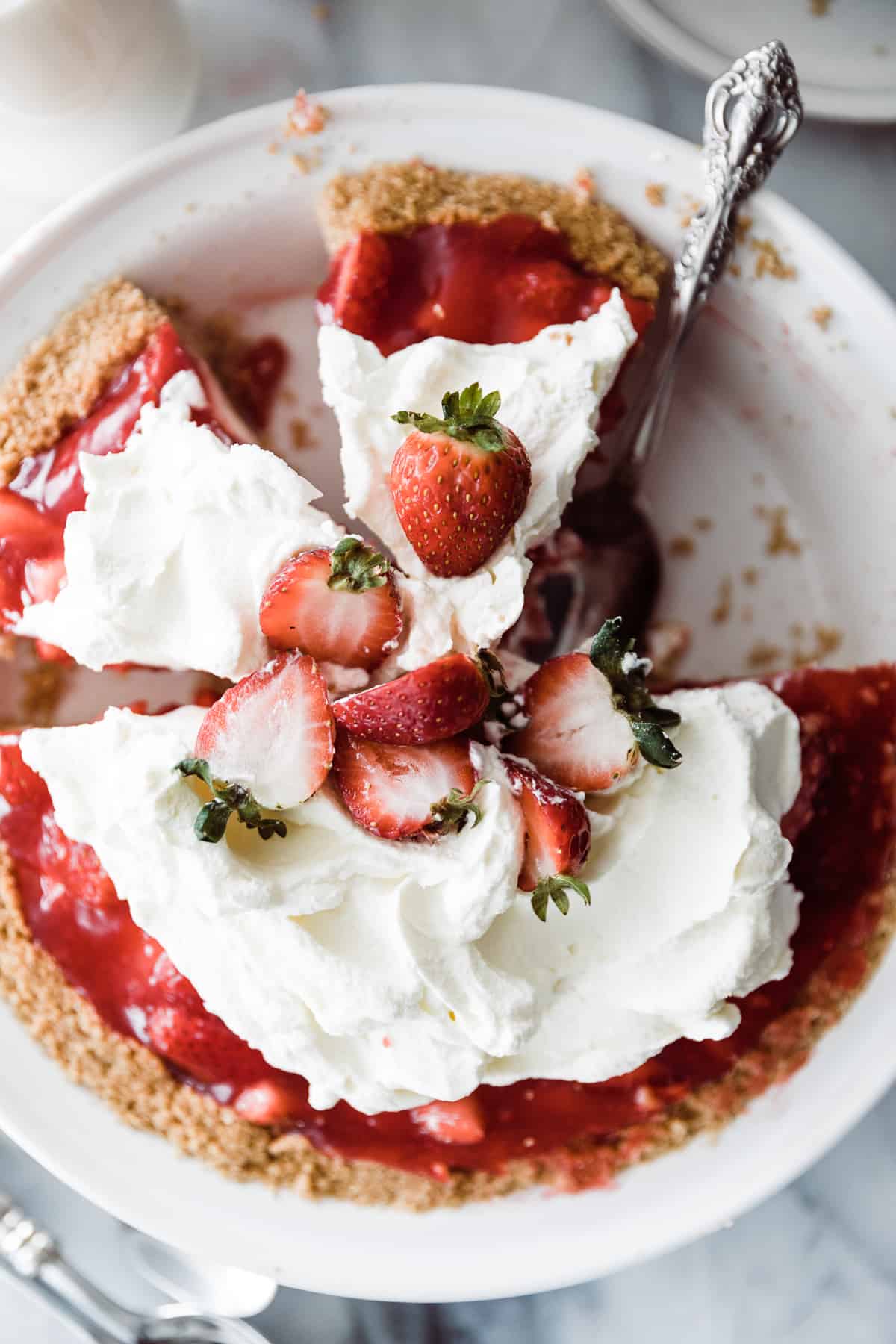 Strawberry cream cheese pie sliced with spoon in pan and a few slices removed. 