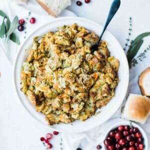 Traditional stuffing with herbs and sage on the table with a spoon in it to serve.