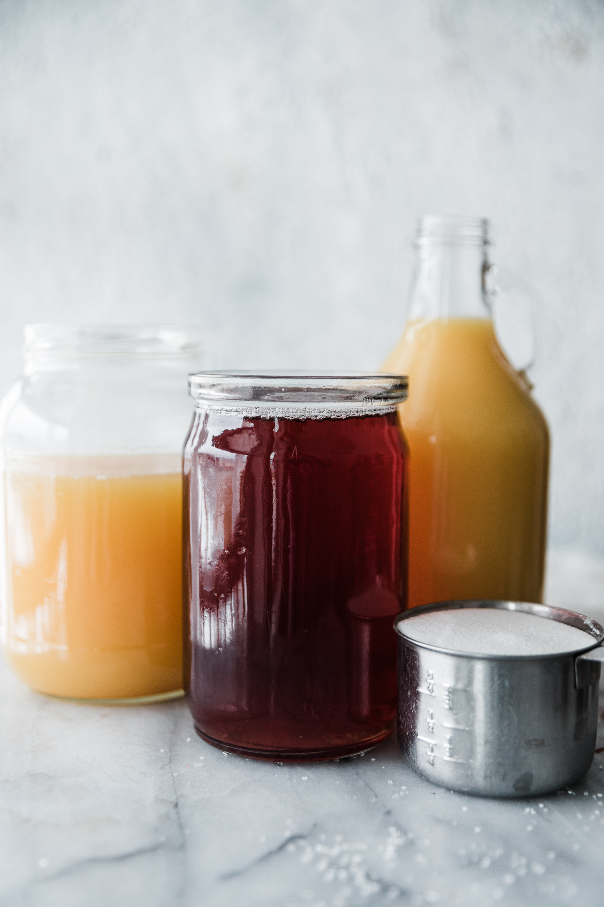 Cranberry juice, orange juice, pineapple juice and sugar in containers. 