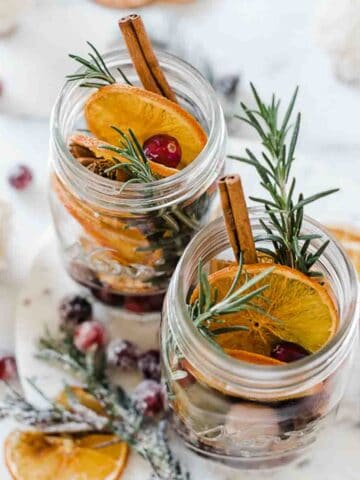 Christmas potpourri in glass mason jars. There are sugared cranberries to the side.