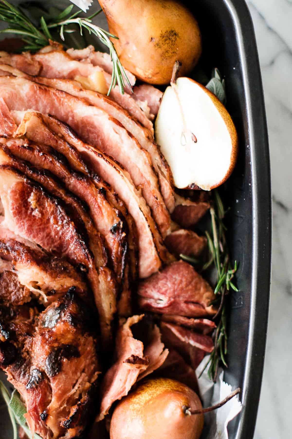 Juicy tender glazed spiral ham in large baking tray with pears. 